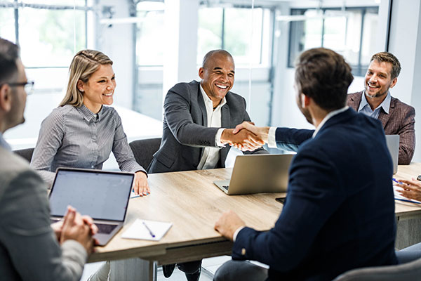 Happy male entrepreneurs came to an agreement during a meeting with their colleagues in the office