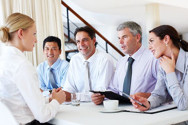 A team of business executives interviewing a young woman