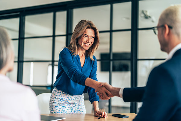 Two professionals shake hands over a signed contract